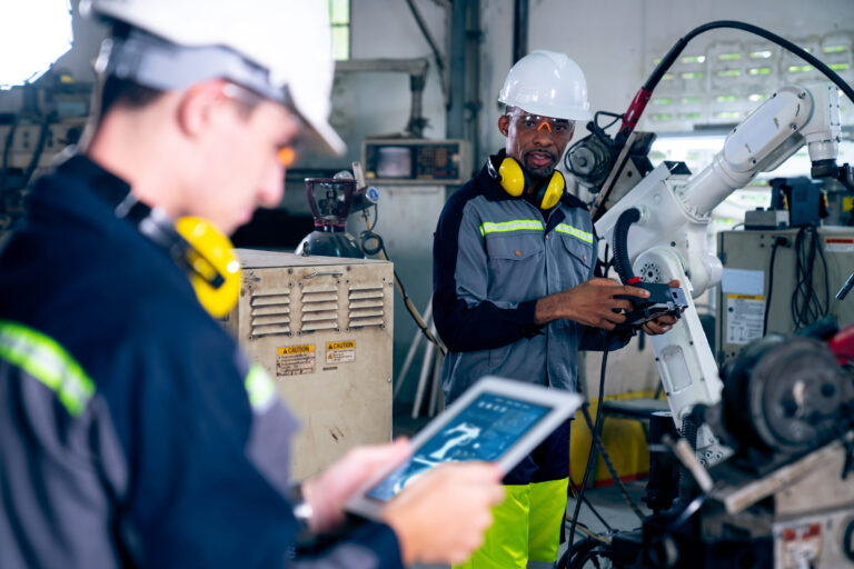 factory workers working with adept robotic arm in a workshop